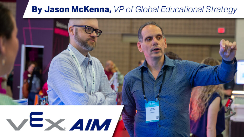 Jason McKenna speaks with a man at a tradeshow. The text reads "By Jason McKenna, VP of Global Educational Strategy. VEX AIM."