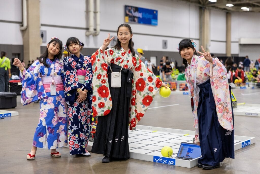 The 4 members of Team DamBare smile and pose while practicing for their matches at the 2025 VEX Robotics World Championship.