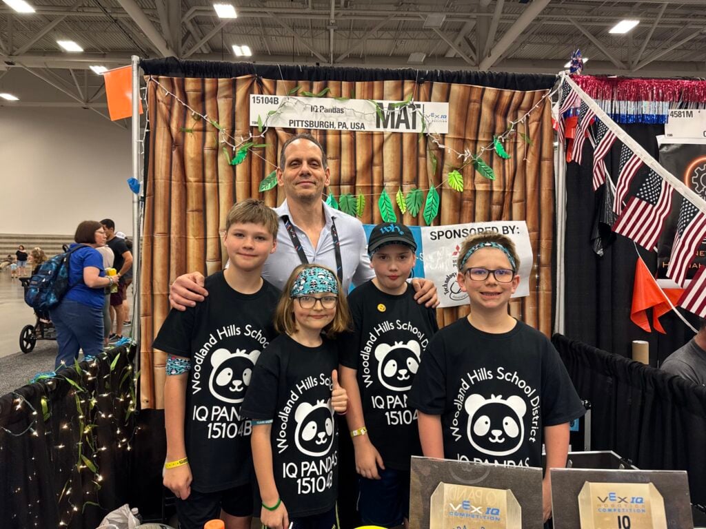 The 4 members of the IQ Pandas smile with VP of Global Educational Strategy, Jason McKenna, at the 2025 VEX Robotics World Championship.