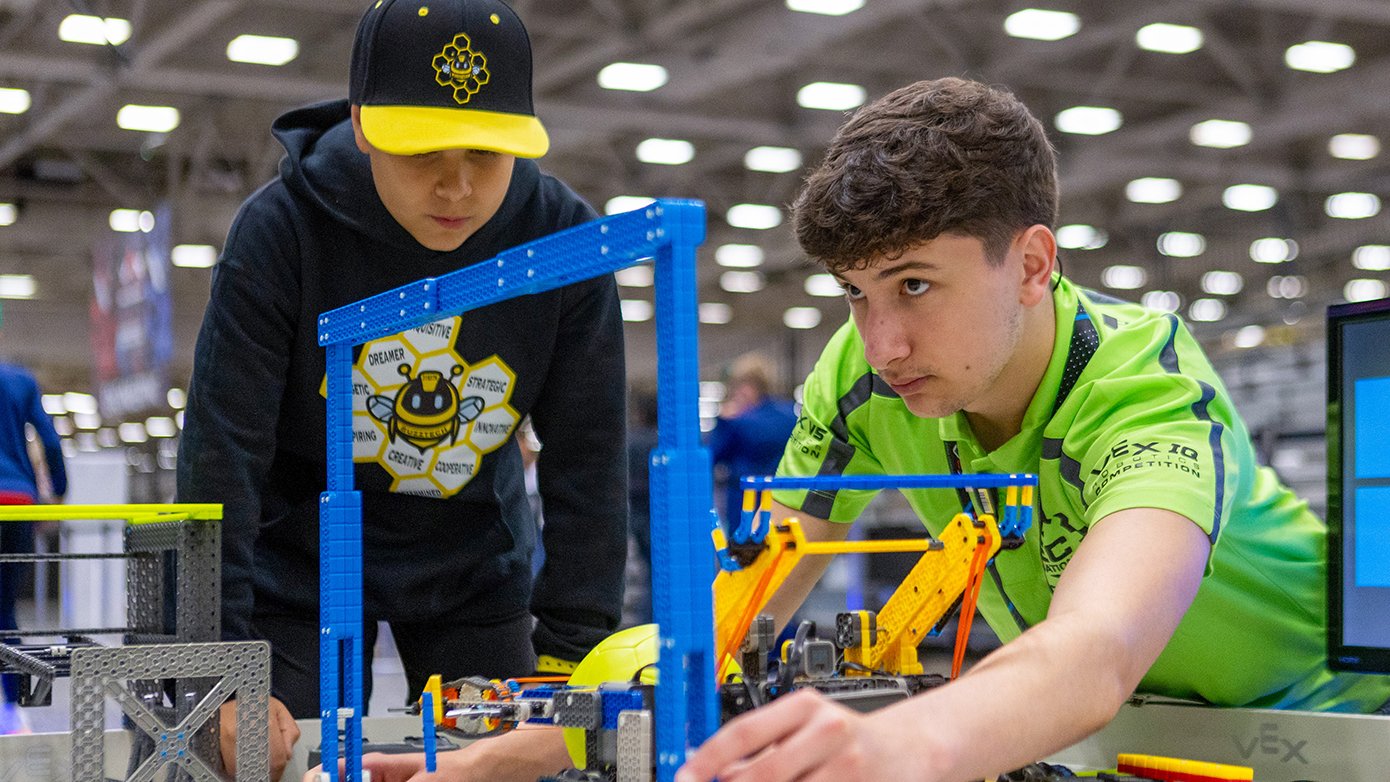 A volunteer checks the measurements of a VEX IQ robot.
