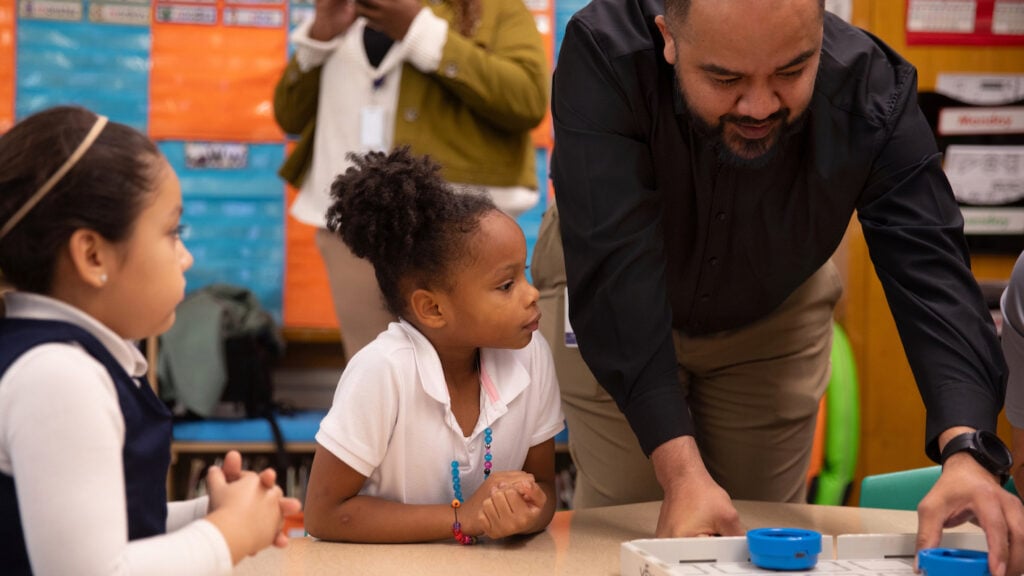 A teacher leads two students in using VEX 123.