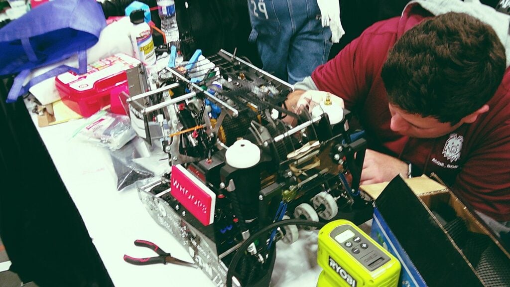 An image by Team WHOOP of a team member working on their robot in their pit.