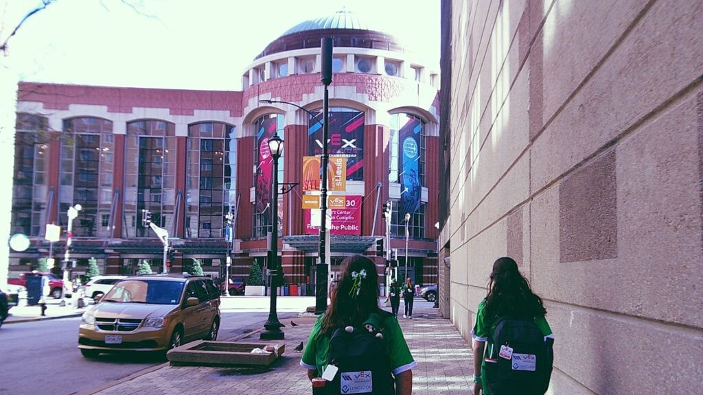An image by Team 64443S The SHS Phoenix of team members walking towards the America's Center venue, which has a dome and VEX Robotics World Championship banners.