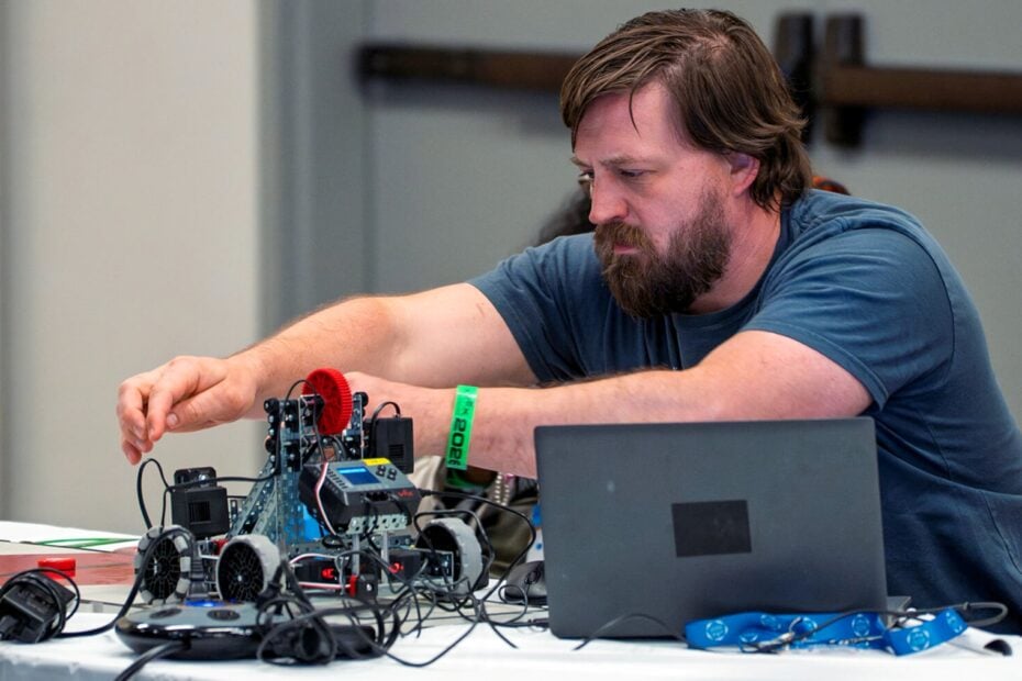 A teacher works on a robot.