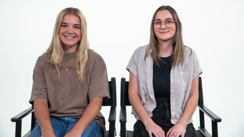 Interns Addie (left) and Niah (right) sit in black chairs in front of a white background.