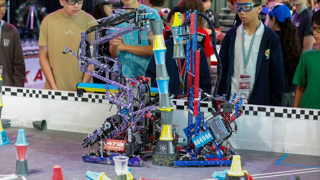Two robots compete in V5RC Override at the Speedway Signature Event.