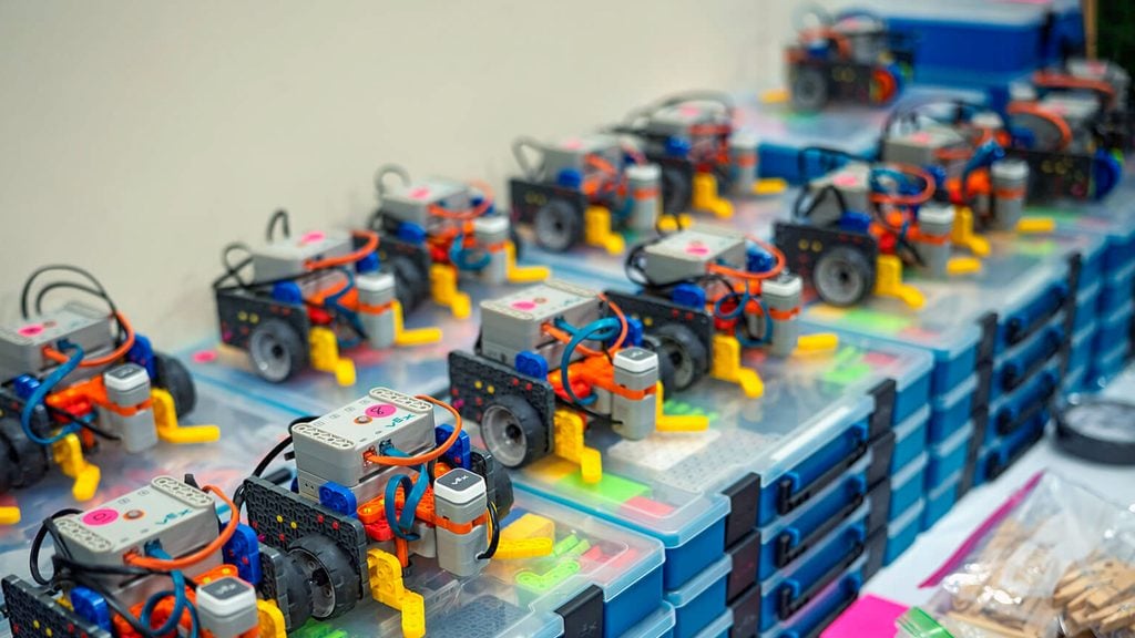 A line of VEX GO robots sit atop kits.