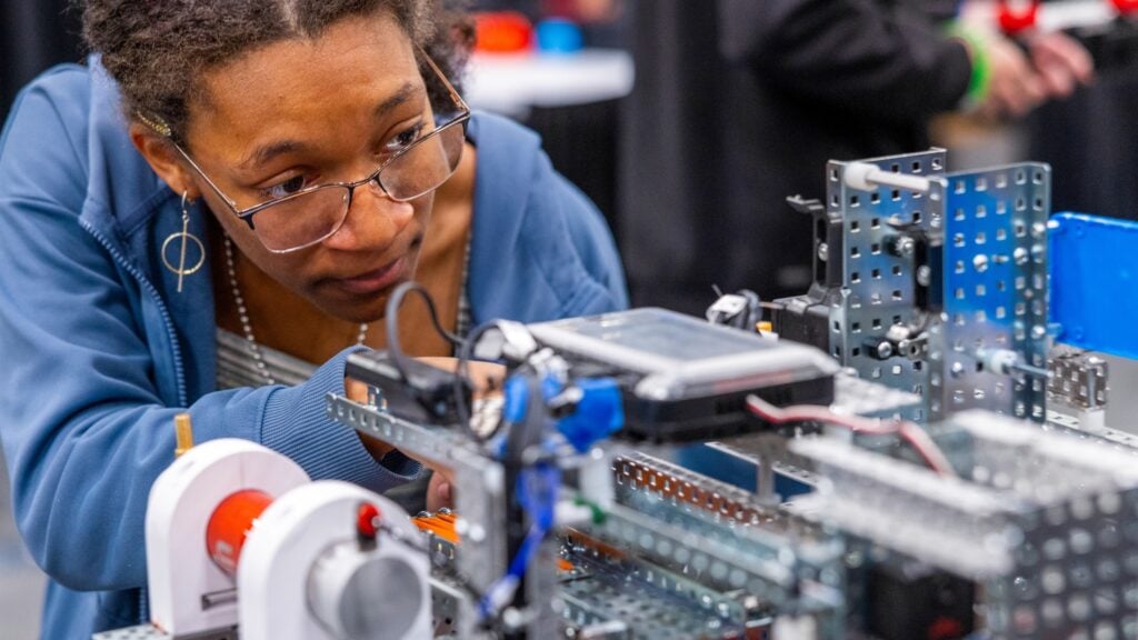 A student leans in to work on a VEX V5 robot.