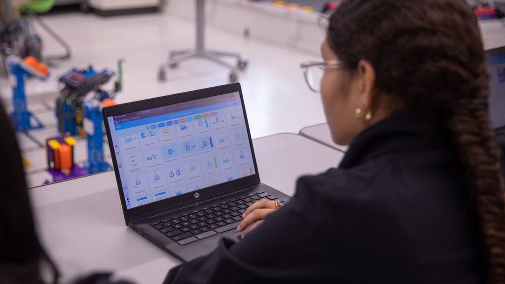 A student works on coding. We see VEXcode pulled up on her screen.